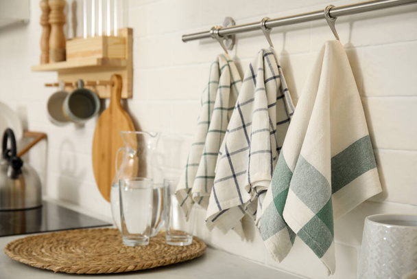 Different clean towels hanging on rack in kitchen - Foto, imagen