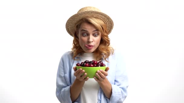 hungry girl farmer in straw summer hat licking lips and eat cherry with hunger, yummy. - Video