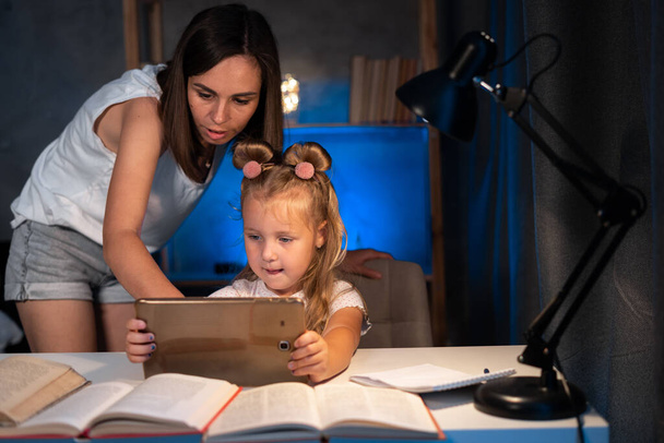 мать и дочь с цифровой планшет делать домашнее задание вместе дома. образование, семья и концепция обучения - Фото, изображение
