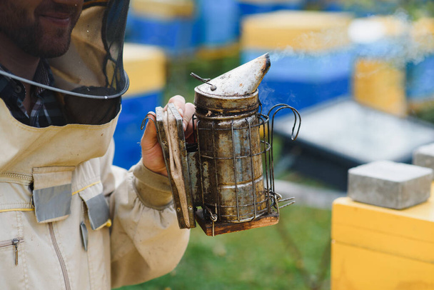 養蜂家の道具だ。養蜂家が蜂と一緒に働くためのすべて。喫煙者、彫刻家、箱、ミツバチからの保護のための養蜂家のスーツ、養蜂のための機器、養蜂のコンセプトを維持. - 写真・画像