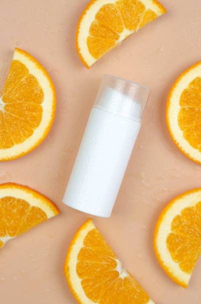 Cosmetics with orange. Orange Moisturizer. Blank white cosmetic tube and orange slices on a beige background. - Zdjęcie, obraz