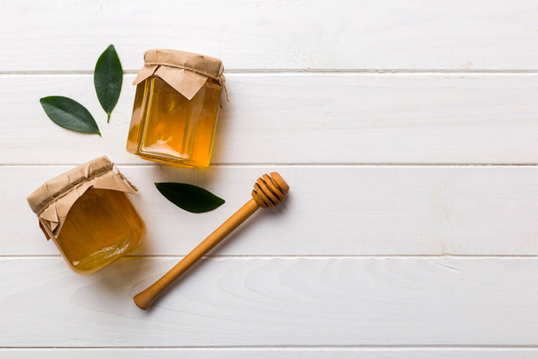 Pot à miel avec trempette à miel en bois sur fond blanc vue de dessus avec espace de copie. Délicieuse bouteille de miel. - Photo, image