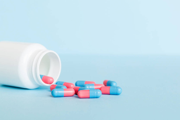 plastic medicine bottle with capsules of pills on colored background. Online pharmacy. Painkiller medicine and antibiotic drug resistance concept. Pharmaceutical industry. - Foto, Imagen