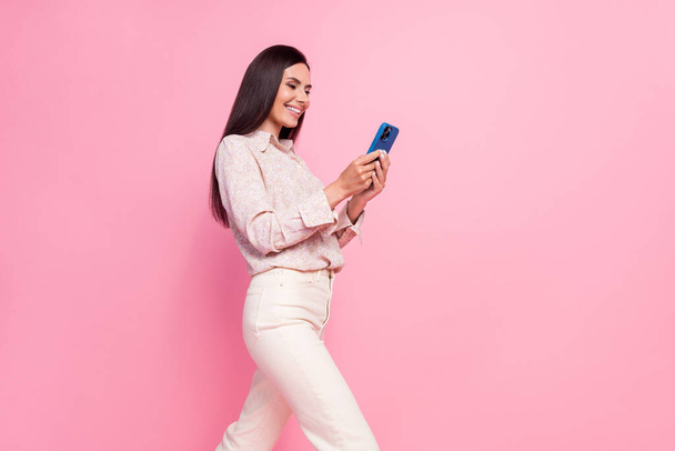 Photo portrait of nice young lady hold telephone walking chatting clients wear stylish formalwear clothes isolated on pink color background. - Foto, Imagen