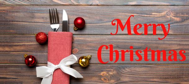 Merry Christmas text. Top view Banner of holiday set of fork and knife on wooden background. Christmas decorations and toys with copy space. New Year Eve concept. - Valokuva, kuva