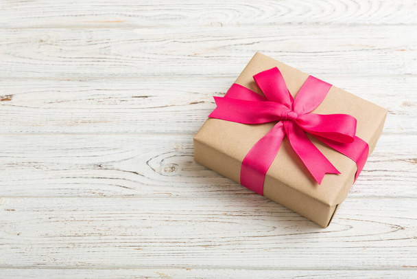 Verpakte kerst of andere vakantie met de hand gemaakt in ambachtelijk papier met gekleurd lint. Aanwezig doos, decoratie van geschenk op tafel, bovenaanzicht met kopieerruimte. - Foto, afbeelding