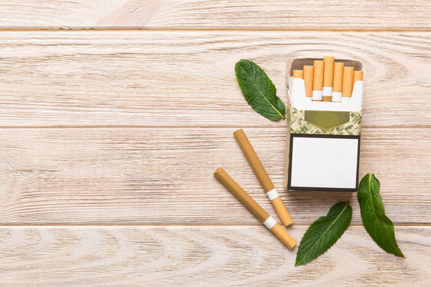 Pack of menthol cigarettes and fresh mint on colored table, Menthol cigarettes top view flat lay. - Photo, Image