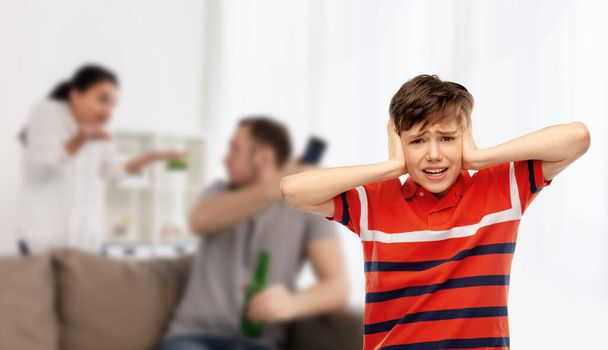 emotional abuse, family issue and violence concept - boy closing his ears with hands over parents fighting on background - Фото, изображение