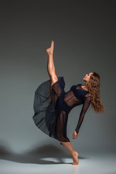 Young beautiful dancer in black dress posing on a dark gray studio background. Modern, Contemporary, improvisation - Foto, Bild