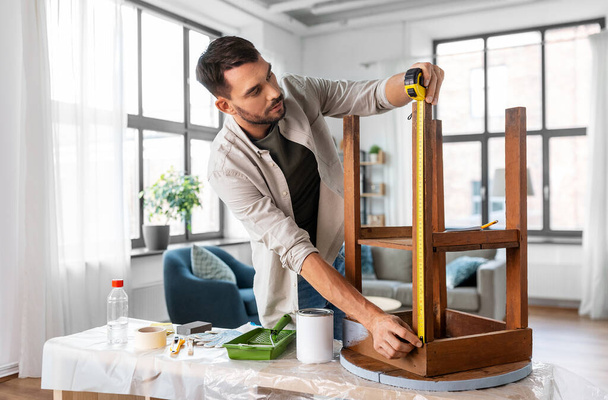 reparação, diy e conceito de melhoria de casa - homem com régua medindo mesa de madeira redonda velha para renovação - Foto, Imagem