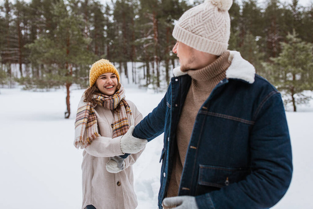 people, love and leisure concept - happy smiling couple walking in winter forest - Foto, imagen