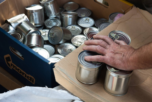 KHARKIV, UKRAINE - Aug. 02, 2022: A box of canned food is seen during the distribution of food to the poor. Volunteer organization Caritas Ukraine distributes food to the needy in Kharkiv - Fotó, kép