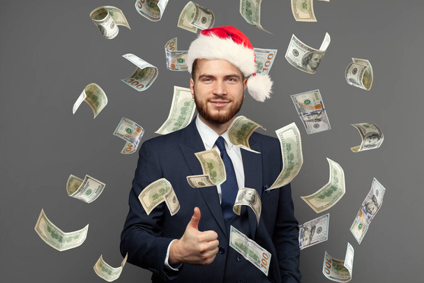 Санта-бизнесмен с деньгами на сером фоне - Фото, изображение