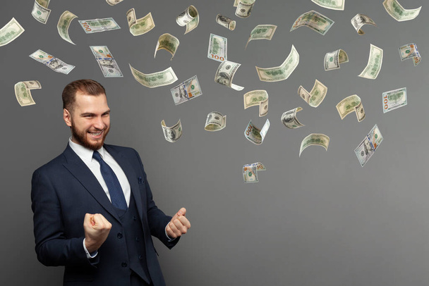 Iloinen liikemies sadan dollarin seteleillä harmaalla taustalla - Valokuva, kuva