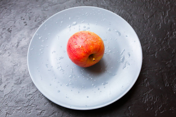 An apple lying on the grey plate. Still life photo. Black background. - Foto, immagini