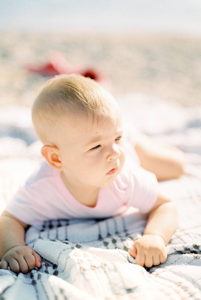 Baby lies with his fists clenched on his tummy on a blanket. High quality photo - Foto, Imagem