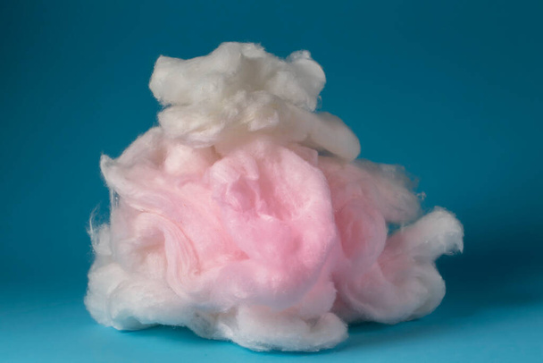 Pink cotton wool on a blue background. A soft pile of fibre.Piece Cotton wool isolated on blue - Foto, Imagem
