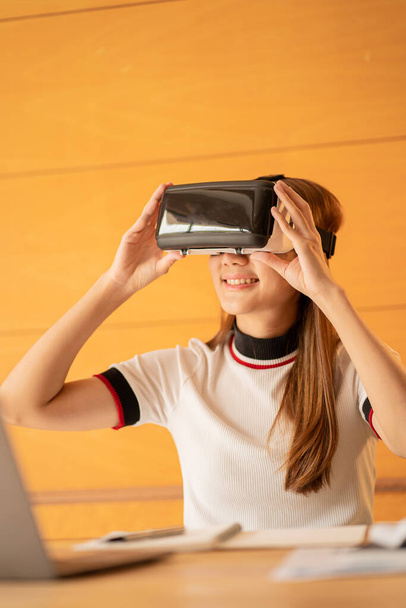 girl sitting on the sofa wearing virtual reality glasses Look at the website online and use the hand-animated 3D simulated screen, future technology concept. - Valokuva, kuva