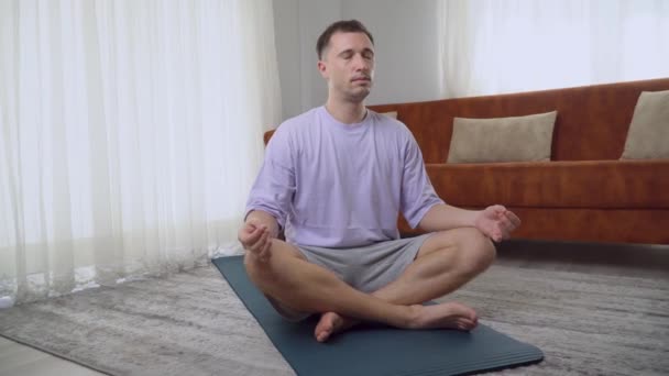 Un hombre hace meditación en casa en la posición del loto, la práctica de la respiración consciente. Imágenes de alta calidad 4k - Metraje, vídeo