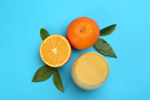 Delicious orange juice and fresh fruits on light blue background, flat lay - Foto, afbeelding