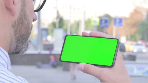 Close Up of Adult Man Holding Horizontal Smartphone with Green Screen Outdoor - 映像、動画