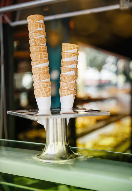 Multiple wafer made ice cream cone, poke at the delicious Italian French gelato gelateria store with defocused blur background - Photo, image