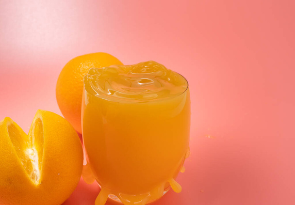 Orange and orange slice. Orange Juice Splashing. Orange on a pink background. Orange close up. - Foto, afbeelding