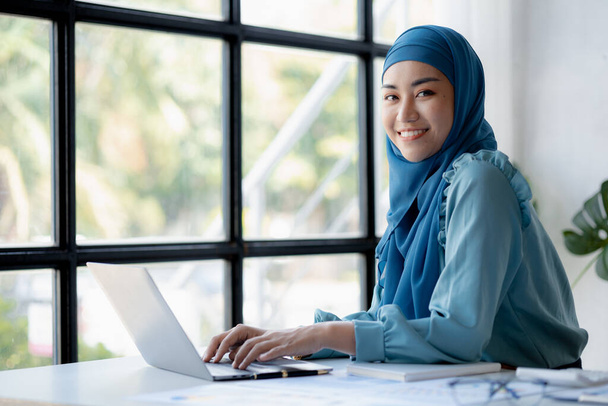 Asian women wearing hijab sitting in the office of a startup company, managed and operated by a young, talented working woman. The management concept drives the company of women leaders to grow. - Photo, image