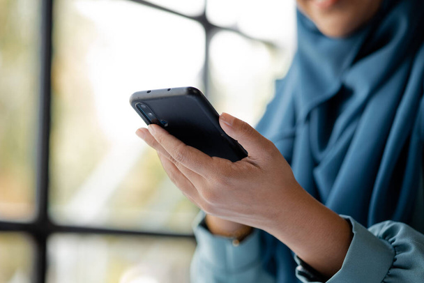 Asian women in hijab are using the mobile phone, administration and operations from the young, smart working women. The management concept drives the company of women leaders to grow. - Foto, afbeelding