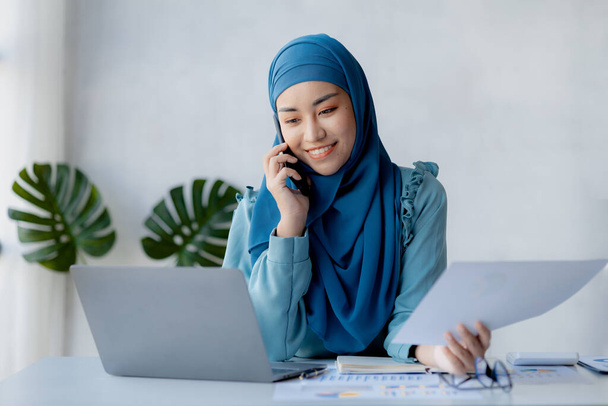 Asian women in hijab are talking on the phone, administration and operations from the new generation, smart working women. The management concept drives the company of women leaders to grow. - Foto, Imagen