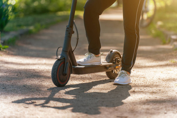 Young woman on an electric scooter on a dirt road in the park. - Foto, imagen