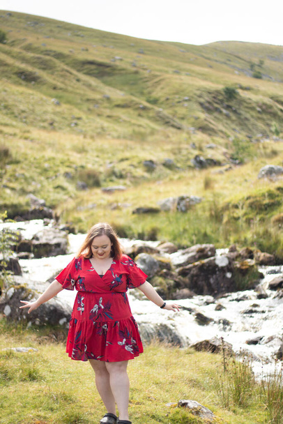 Plus size woman with brunette hair, wearing a red dress while on a travel adventure - Foto, Bild