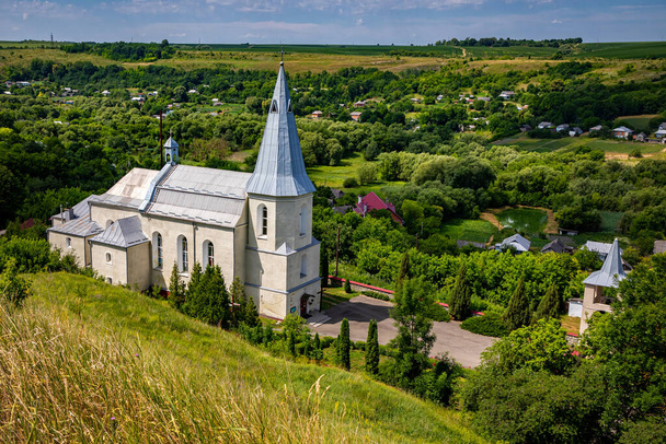 Iglesia católica en el pueblo ucraniano de Zinkiv. Paisaje rural con una hermosa iglesia en un día de verano. - Foto, Imagen