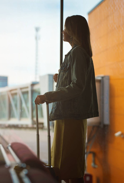 Жінка з багажем чекає на рейс в аеропорту
. - Фото, зображення