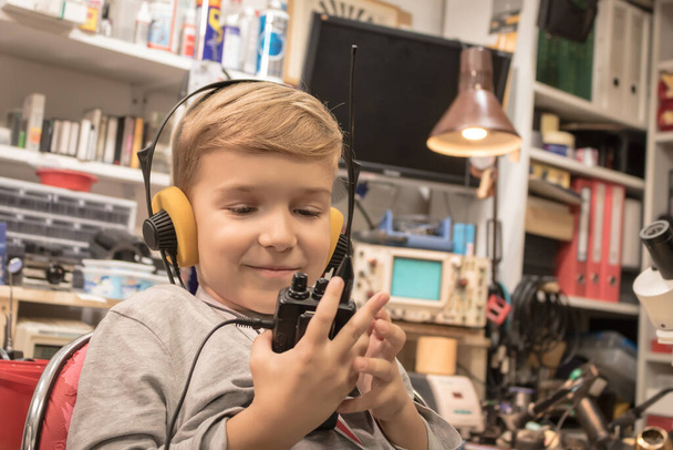 Happy kid with head phones talking over CB radio in amateur radio station. Smiling boy using walkie talkie. - Foto, Bild
