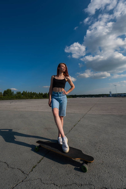 Young caucasian woman riding a longboard outdoors - Photo, image