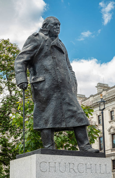 London, UK - July 4, 2022: Parliament Square Gardens. Closeup of Bronze statue of Winston Spencer Churchill on gray pedestal under blue cloudscape. Green foliage in back. - Photo, image