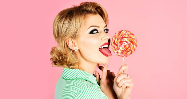 Girl licking lollipop. Beautiful woman with red lips eat sweats lolly pop. Sexy model sucking candy - Zdjęcie, obraz