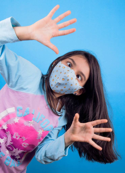 Little funny girl with a medical black mask.Coronavirus blue background. Funny expression. Covid-19. panorama background. Stop covid-19 - Photo, Image