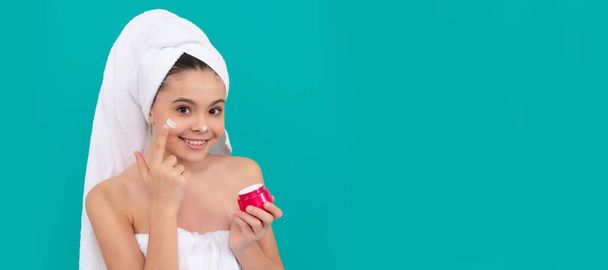 Girl with healthy skin, facial treatment, funny child in bath tower applying face cream, healthy skin. Cosmetics and skin care for teenager child, poster design. Beauty kid girl banner with copy space - Foto, Bild