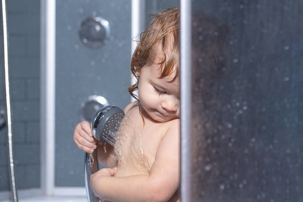 Child bathing in bathroom. Kid with soap suds on hair taking bath. Closeup portrait of smiling kid, health care and kids hygiene - Foto, Bild