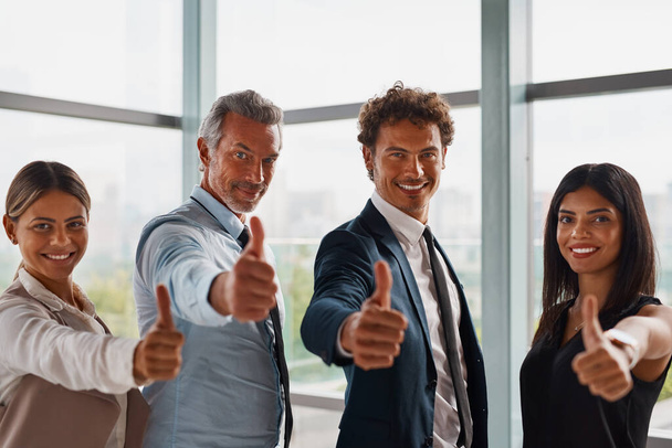Αντίχειρες μέχρι τη δημιουργία μιας επιτυχημένης επιχείρησης. εταιρικοί επιχειρηματίες δείχνουν αντίχειρες επάνω στο γραφείο - Φωτογραφία, εικόνα