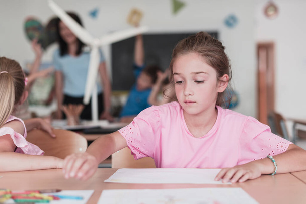 Little girls sitting in elementary school drawing on paper with their friends while sitting in a modern classroom. High quality photo - Foto, immagini