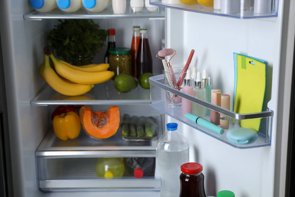 Storage of cosmetics and tools in refrigerator door bin next to groceries - Foto, Bild