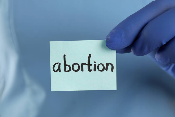 Doctor holding paper card with word ABORTION, closeup - Fotó, kép