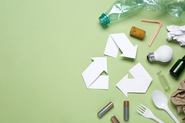 Recycling symbol and garbage on light green background, flat lay. Space for text - Zdjęcie, obraz