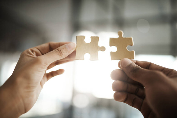Teamwork, unity and growth with puzzle pieces in the hands of business people building, growing and working together as a team. Closeup of colleagues showing togetherness and synergy from below. - Foto, imagen