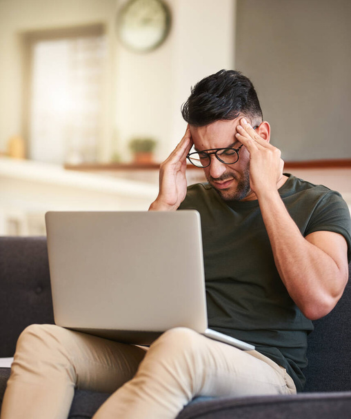 Что это за внезапная острая боль? красивый молодой человек, страдающий головной болью во время работы над ноутбуком дома - Фото, изображение