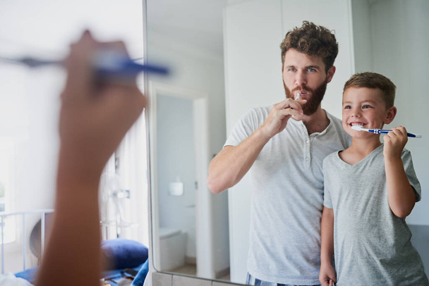 Віддати зуби добре чистим. батько і його маленький син чистять зуби разом у ванній вдома
 - Фото, зображення