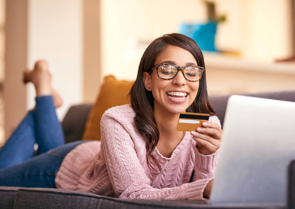 Shes the first to scoop up the latest deals. an attractive young woman using a laptop and credit card on the sofa at home - Foto, Imagen
